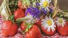 Strohkorb mit Blumen und Erdbeeren