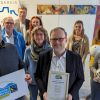 Landrat Jens Womelsdorf und Mitglieder der Steuerungsgruppe Fairtrade halten die Urkunde zur Titelerneuerung und Fairtrade-Bälle hoch. 